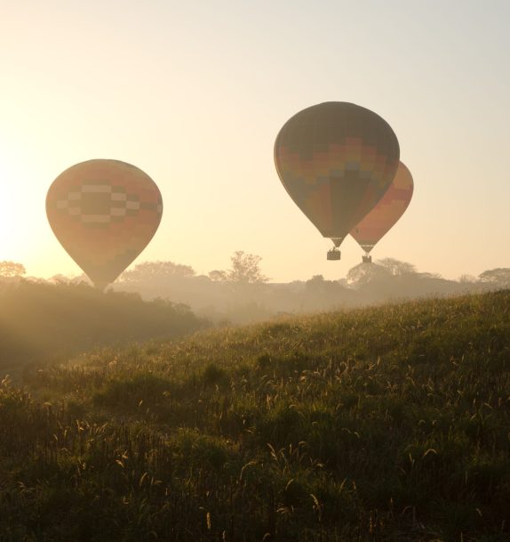 Three,Hot,Air,Balloons,Flying,Over,The,Hills,At,Sunrise
